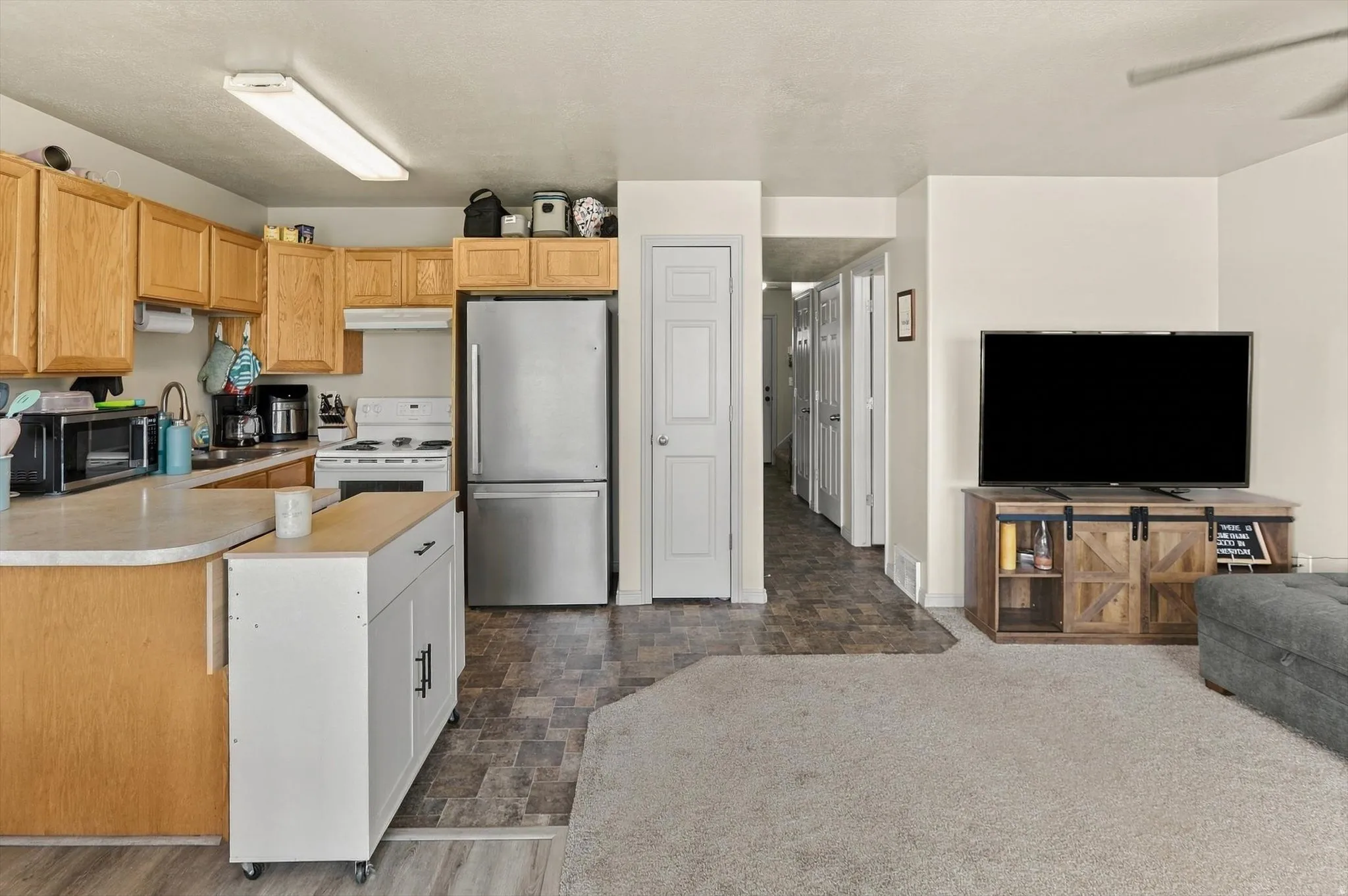 Kitchen featuring wood-finish cabinetry, white appliances, and a stainless steel refrigerator