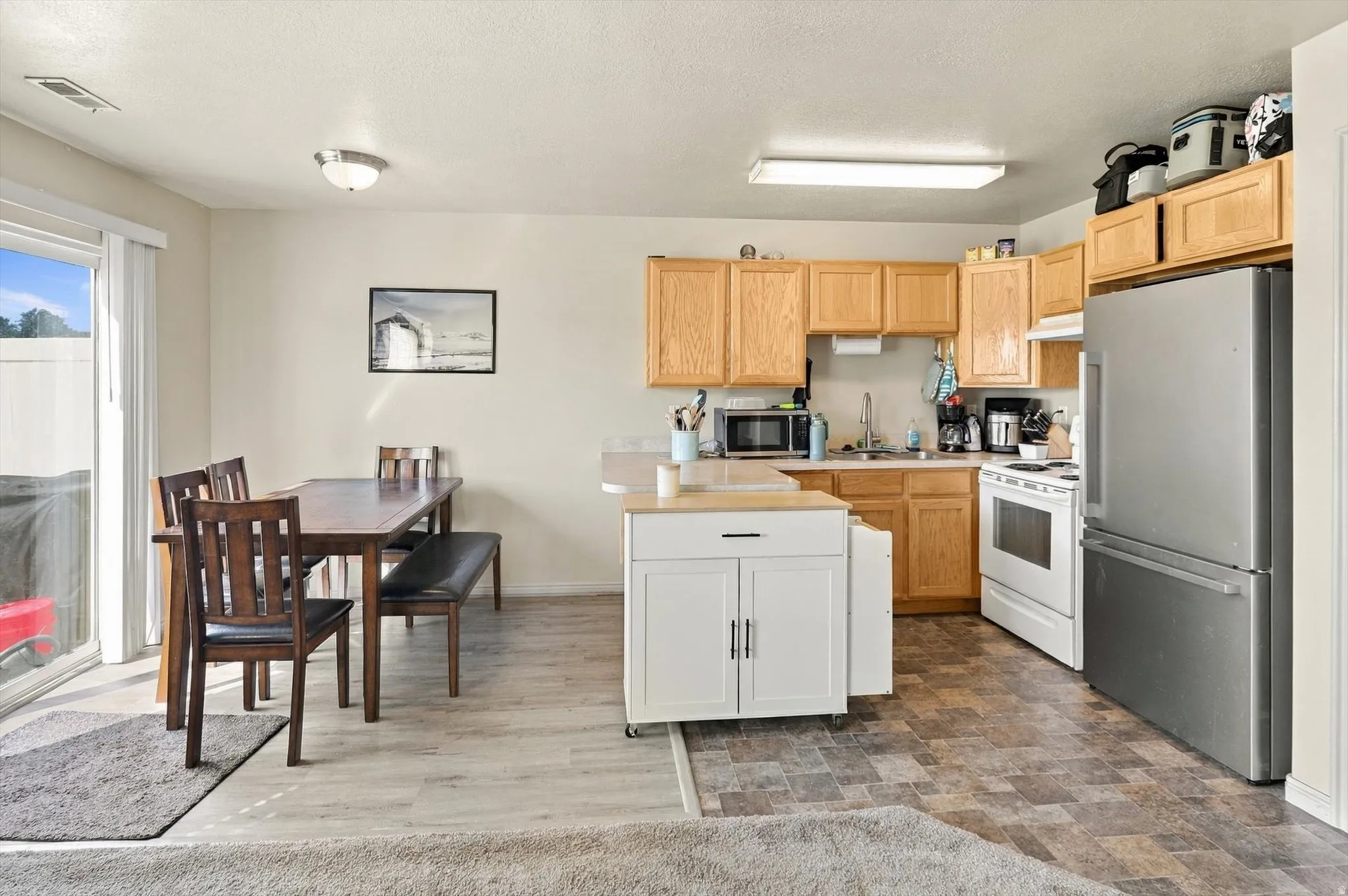 Kitchen with wood-finish cabinetry, stainless steel refrigerator, and white range