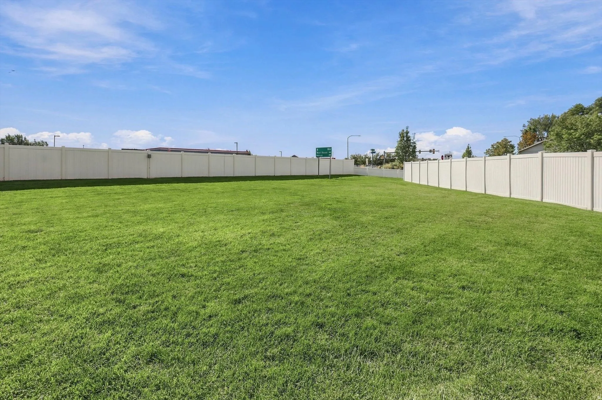 Expansive green lawn featuring a perimeter privacy fence