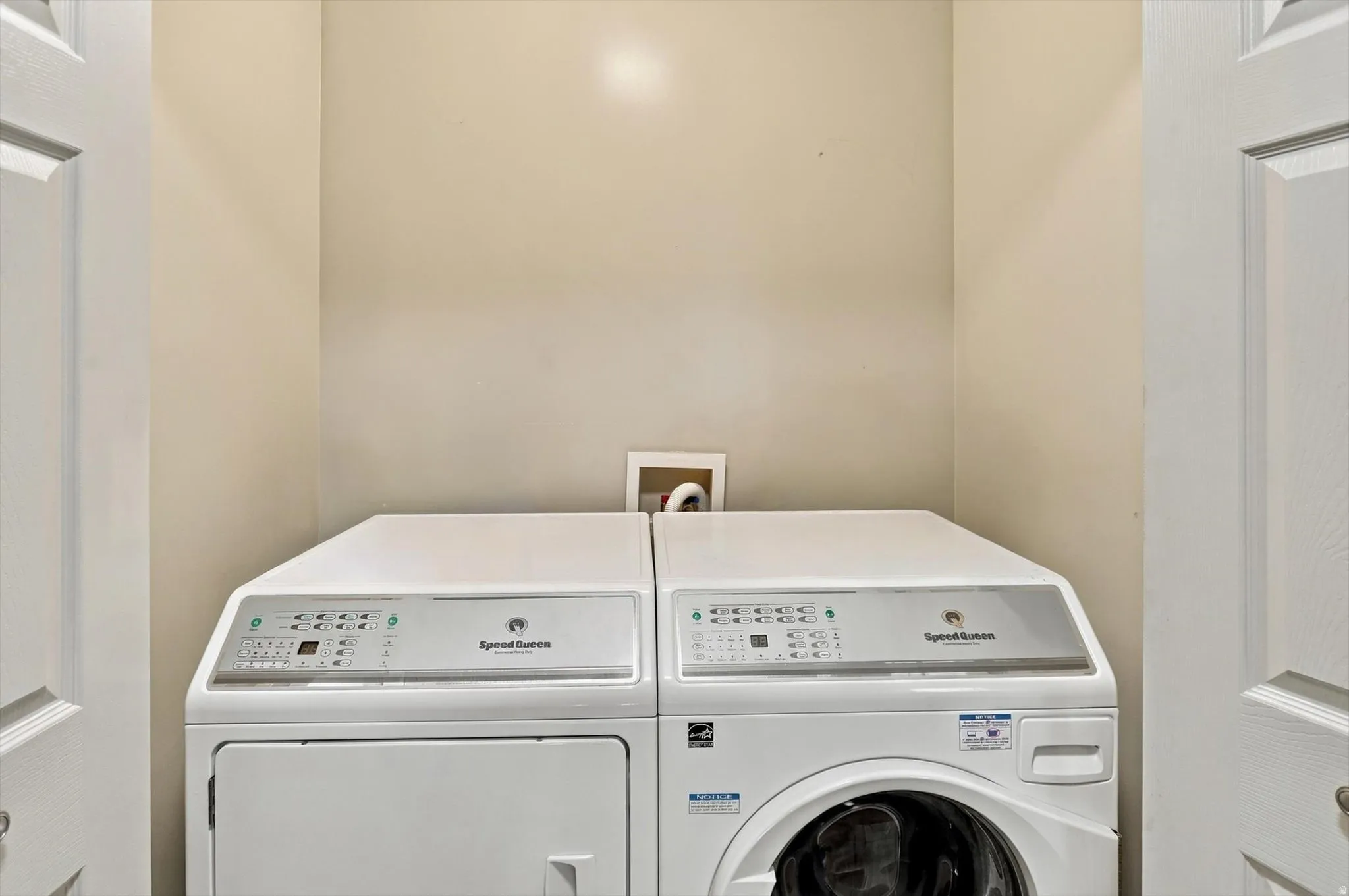 Laundry area featuring a stacked washer and dryer, painted walls, and paneled doors