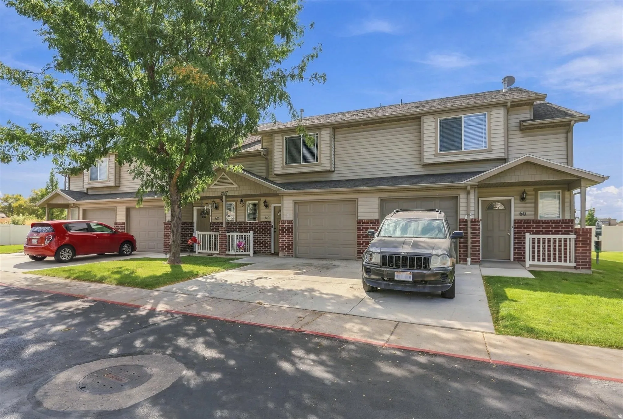 Exterior featuring neutral-toned siding, brick accents, a covered entry, and an attached garage