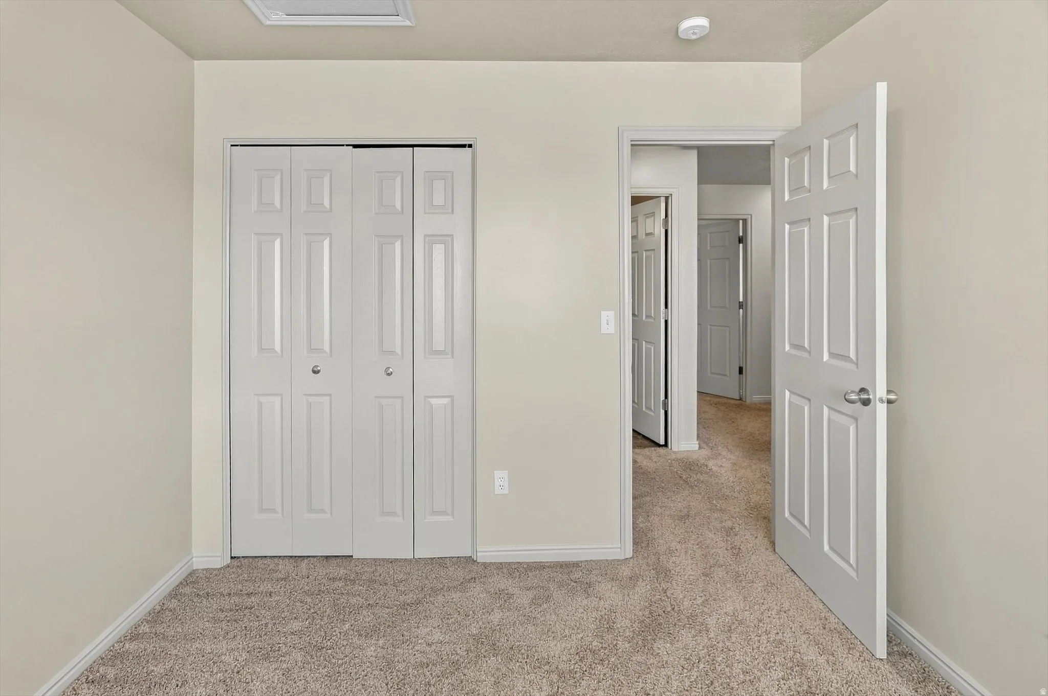 Neutral wall tones with carpet flooring, a bi-fold closet door, and a paneled interior door
