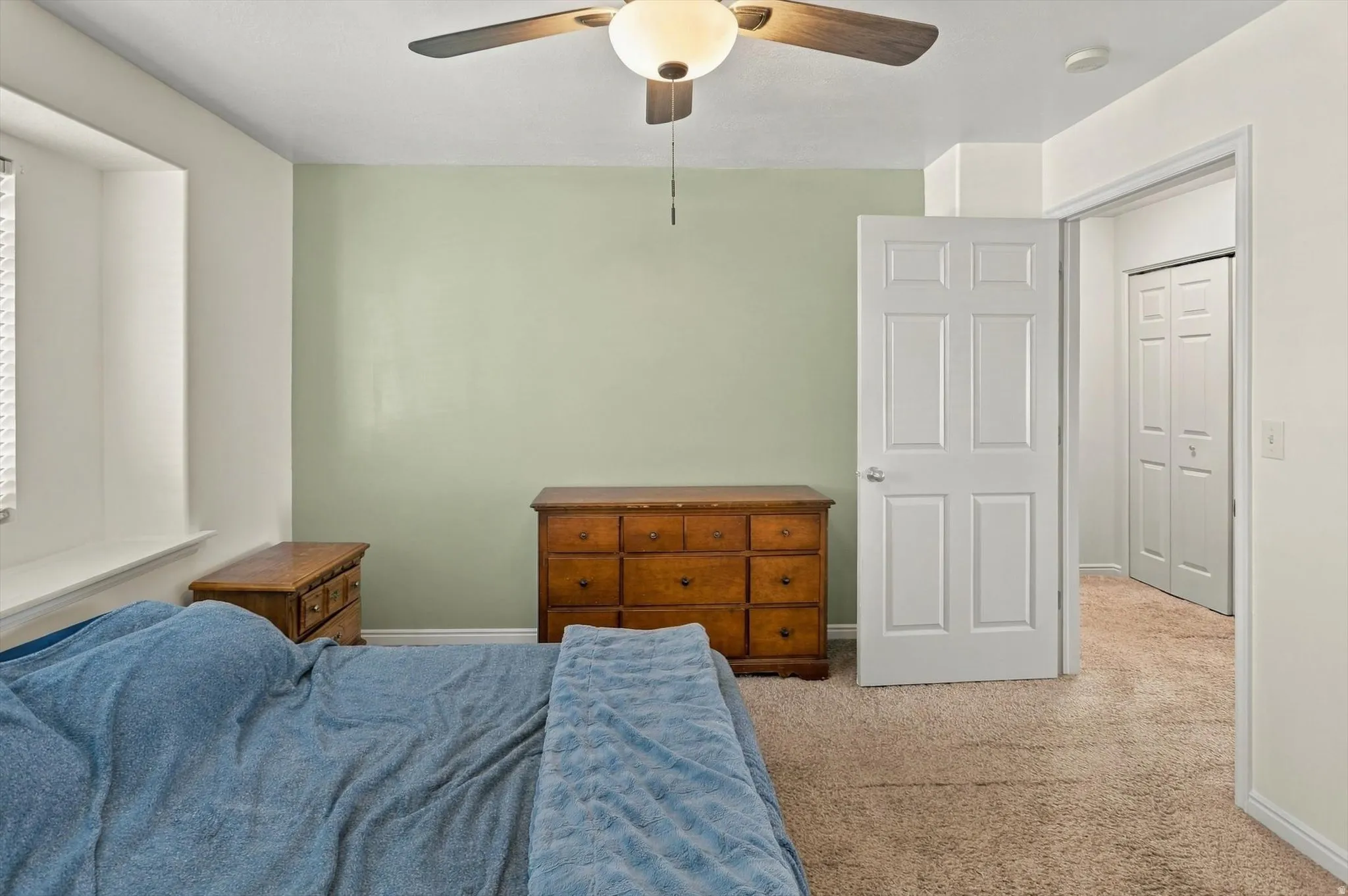 Neutral-toned carpeting, ceiling fan with integrated lighting, window with deep sill, and white paneled doors
