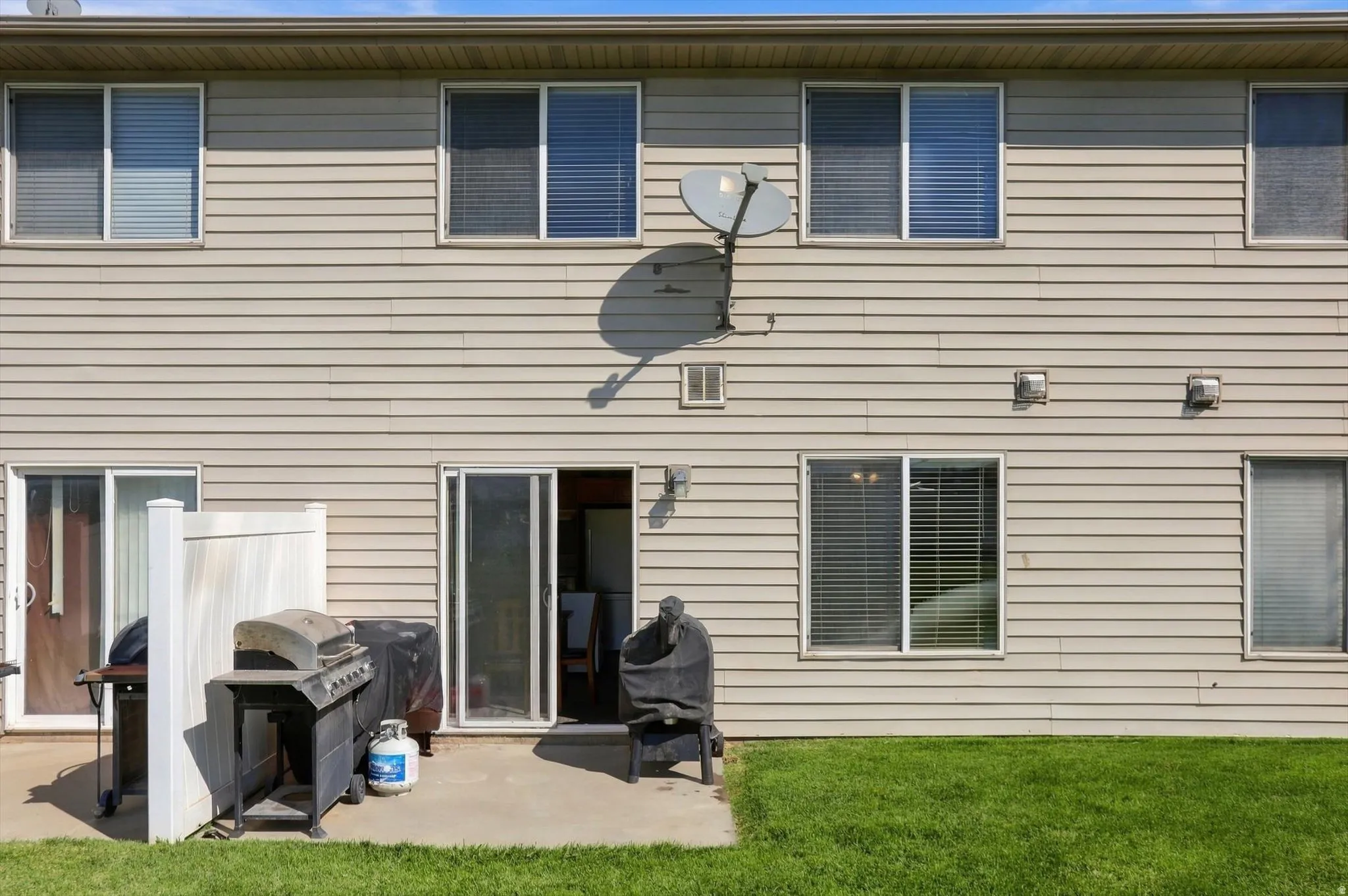 Exterior featuring light-colored horizontal siding, a concrete patio, and sliding glass doors