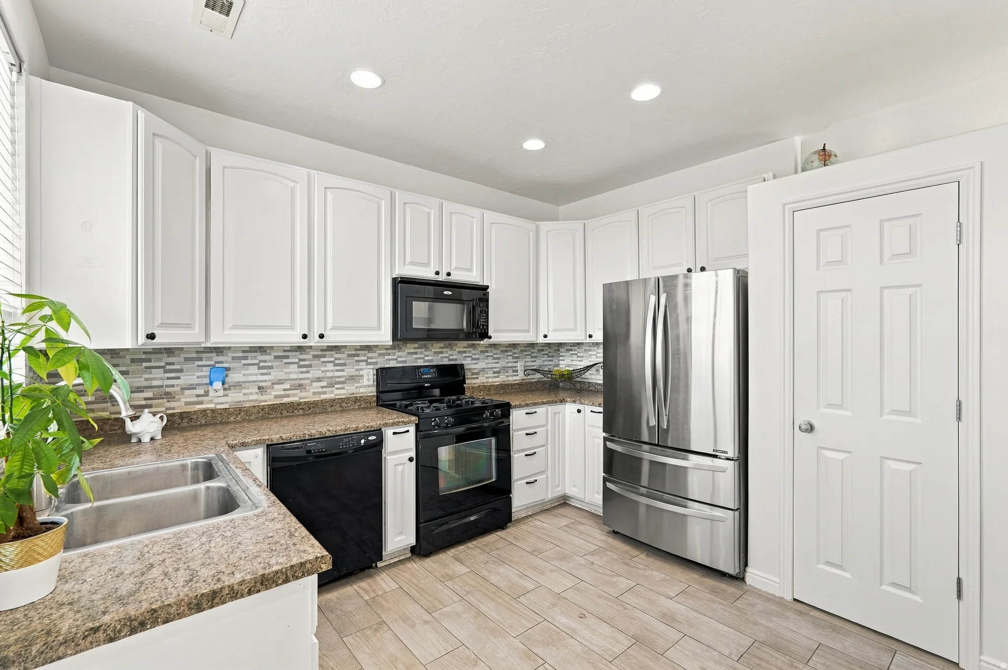 Kitchen featuring white cabinetry, backsplash,  countertops, stainless steel refrigerator, and wood-finish flooring