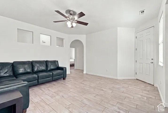 Spacious living area featuring wood-look tile flooring, a multi-light ceiling fan, and decorative wall cutouts