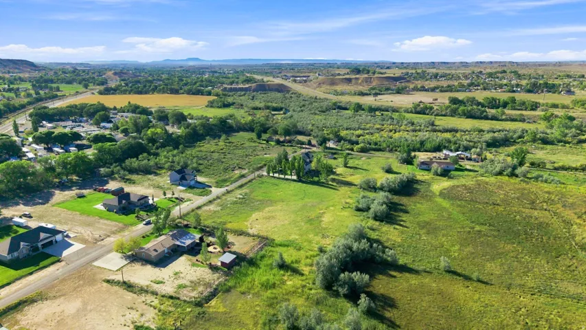 Expansive rural landscape featuring distant mountains and scattered residential properties