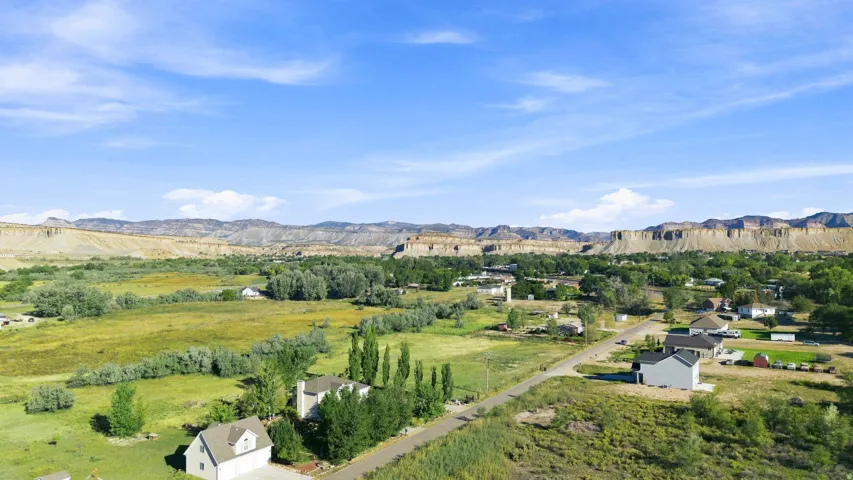 Expansive landscape featuring distant bluffs, established trees, and open green areas