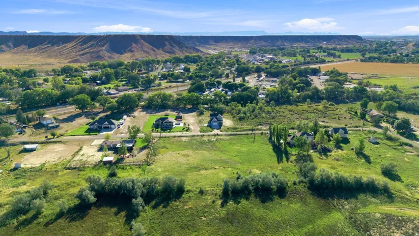 Expansive landscape featuring distant mountainous terrain, scattered residential properties, and diverse mature trees