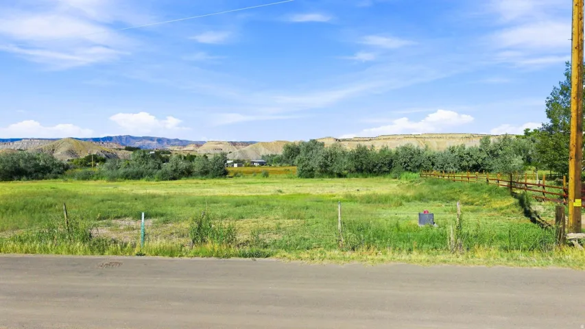 Expansive open land with natural ground cover, mature trees, and a distant mountain range