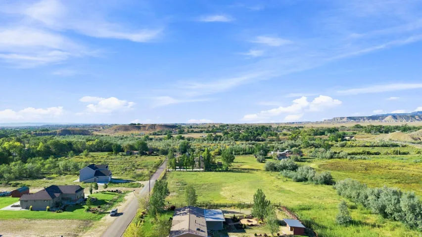 Expansive rural setting with distant natural formations, mature trees, and open green spaces