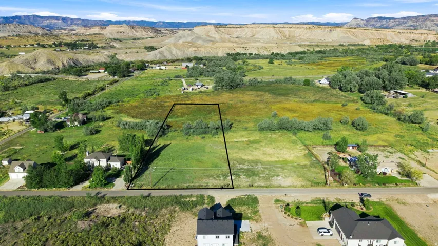Expansive land parcel featuring open fields, distant mountain formations, and established trees