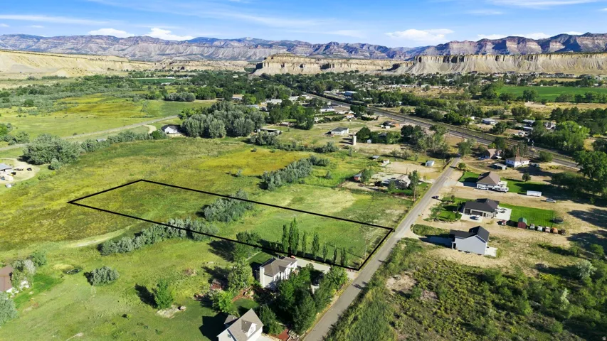 Expansive land parcel featuring open green space, mature trees, and direct road frontage