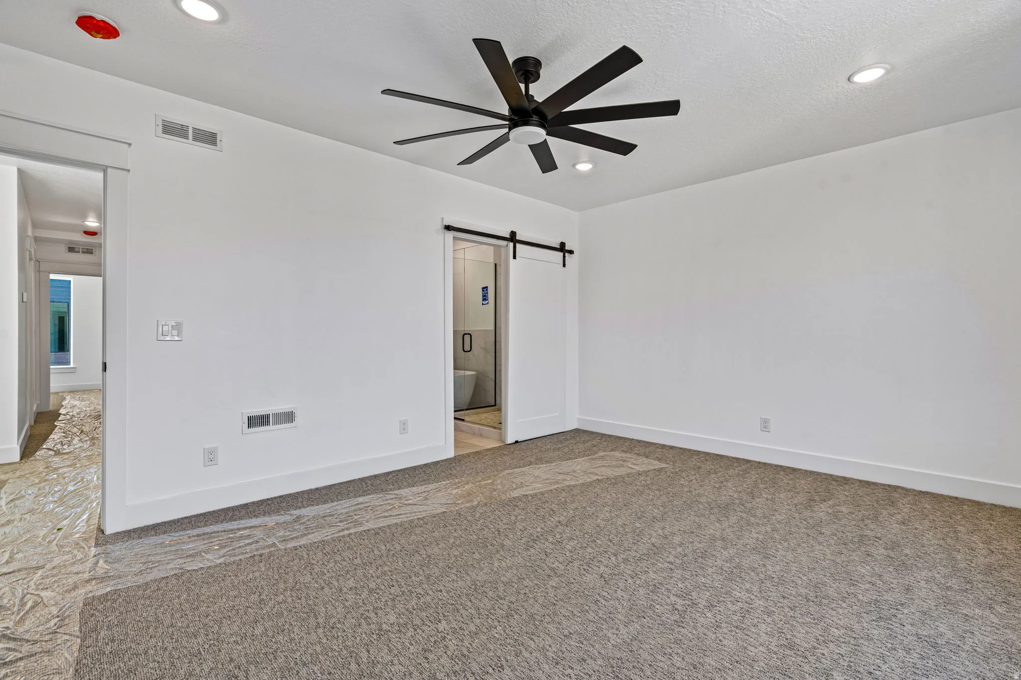 Recessed ceiling lighting, modern ceiling fan, white walls, and gray carpet
