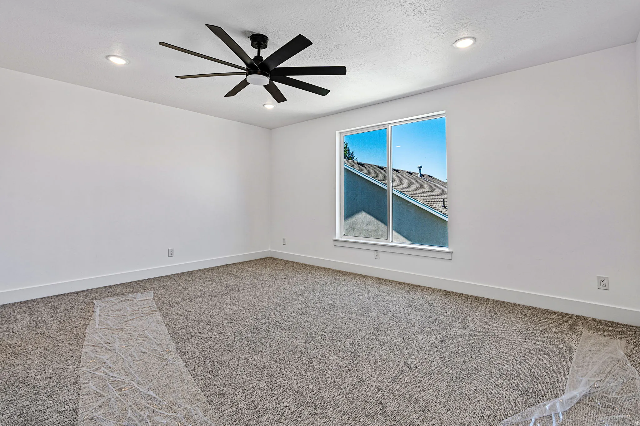 Recessed ceiling lighting, ceiling fan, carpet flooring, and a large window