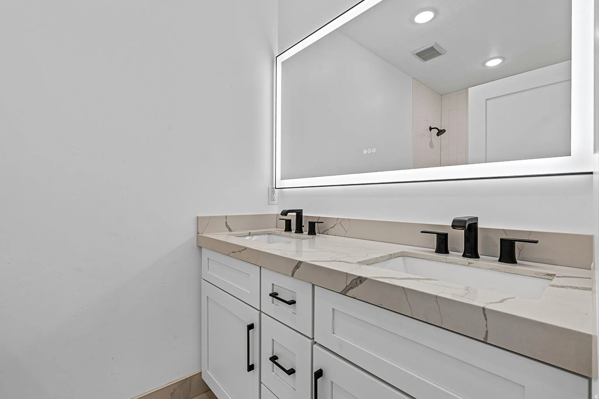 Dual basin vanity with white cabinetry, matte black hardware, and integrated sinks