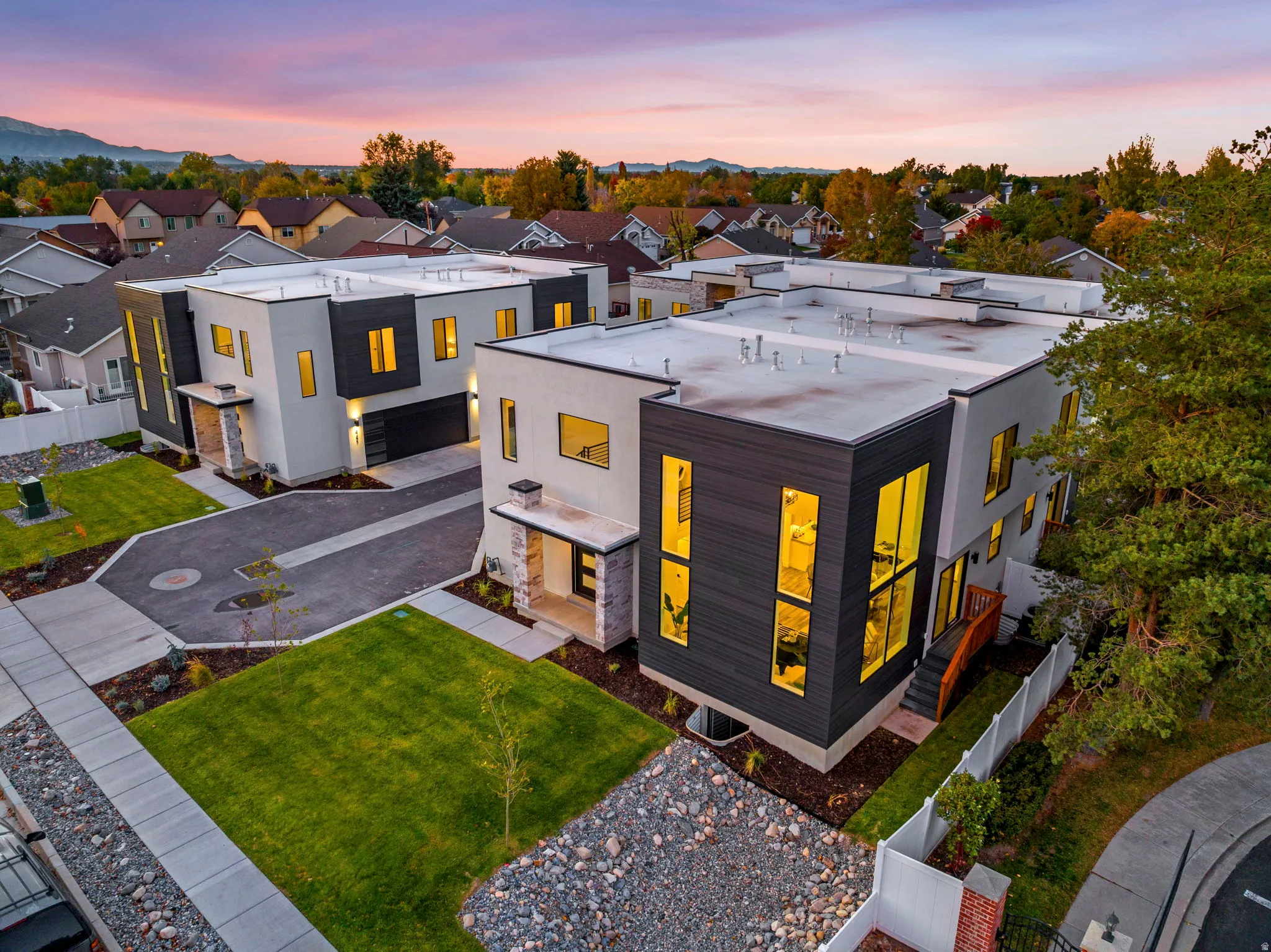 Modern architectural design featuring contrasting facade materials, attached garages, stone accents, and manicured landscaping