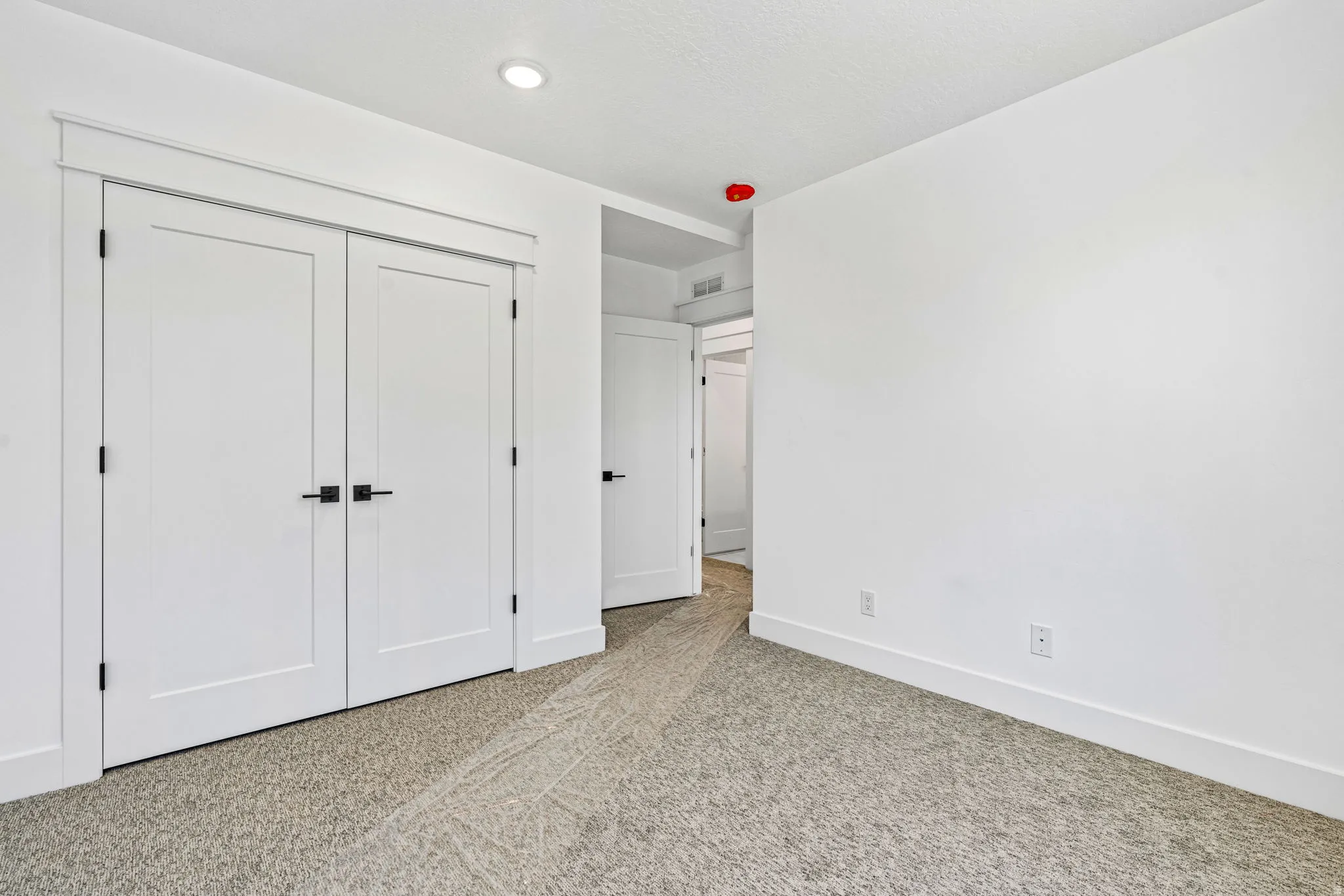 Neutral color palette with textured carpeting, recessed lighting, and white trim
