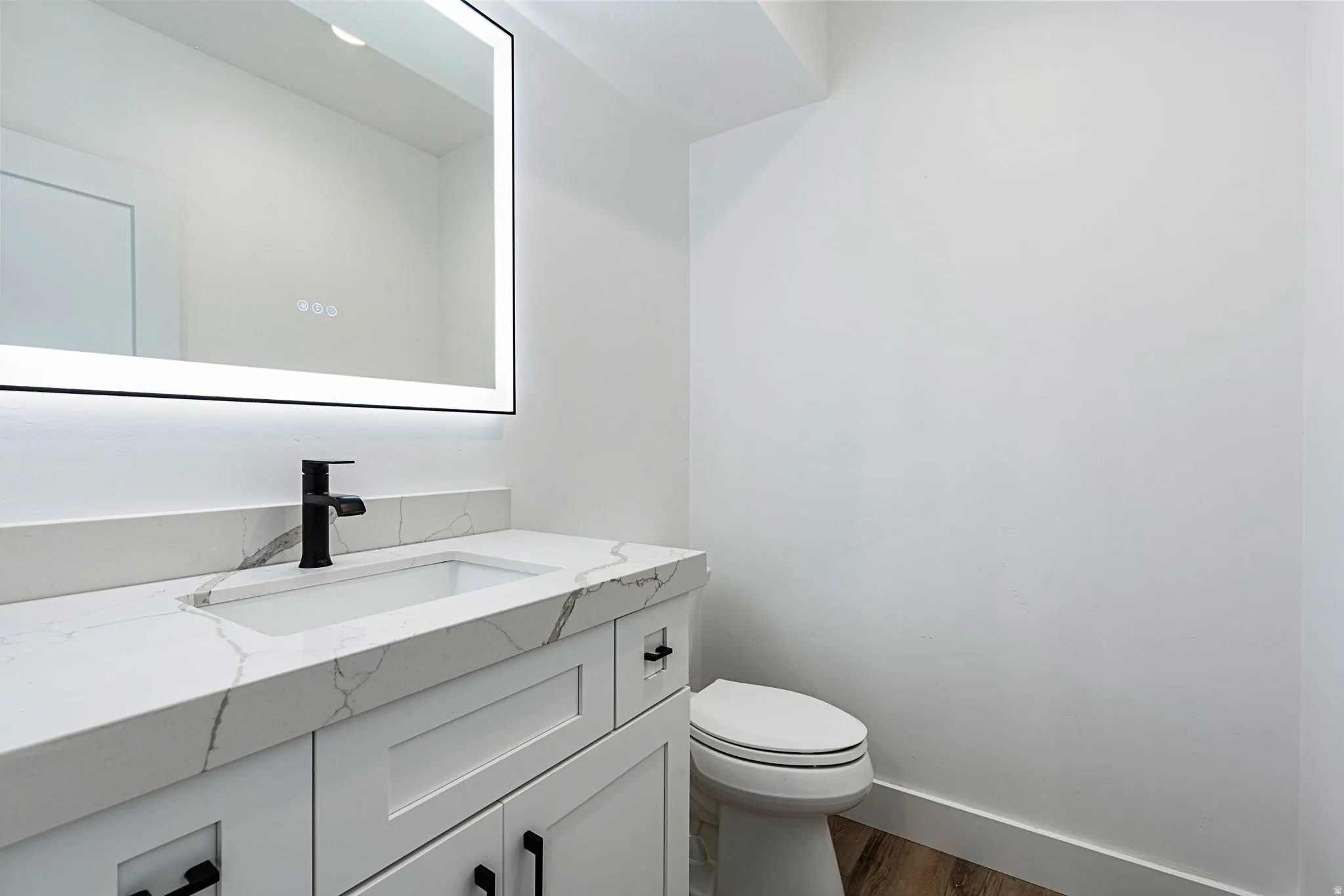 White vanity with shaker-style cabinetry, matte black hardware, integrated sink, and quartz countertop