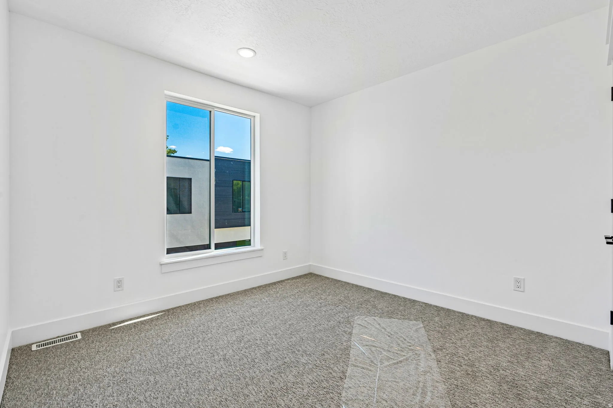 Bright interior space featuring a window, recessed lighting, and soft gray carpeting