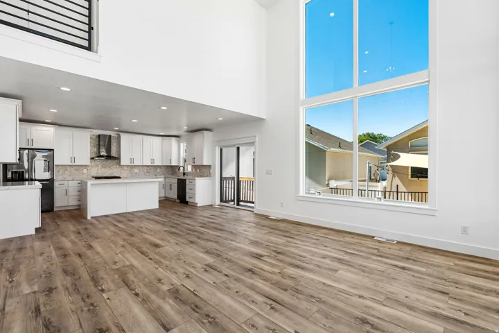 Open-concept living area with a two-story ceiling, expansive floor-to-ceiling windows, and wood-finish flooring
