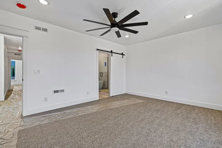 Recessed ceiling lighting, modern ceiling fan, white walls, and gray carpet