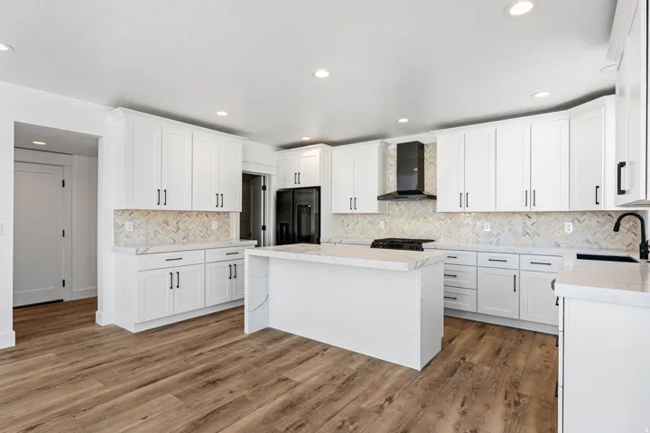 Kitchen featuring wood-finish flooring, white cabinetry, a central island, patterned backsplash, and recessed lighting