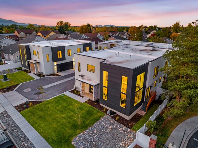 Modern architectural design featuring contrasting facade materials, attached garages, stone accents, and manicured landscaping