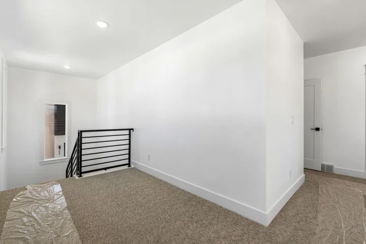 Carpeted landing with white walls and recessed lighting