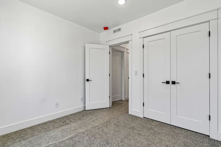 Neutral-toned carpeting, white walls, white doors with matte black hardware, and recessed ceiling lighting