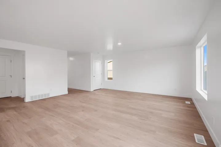 Spacious room with wood-finish flooring, white walls, and multiple windows