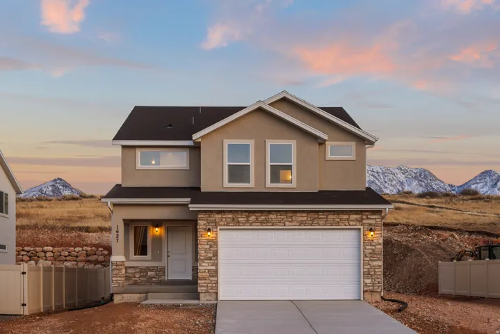 Two-story stucco exterior with stone accents, attached two-car garage, and concrete driveway