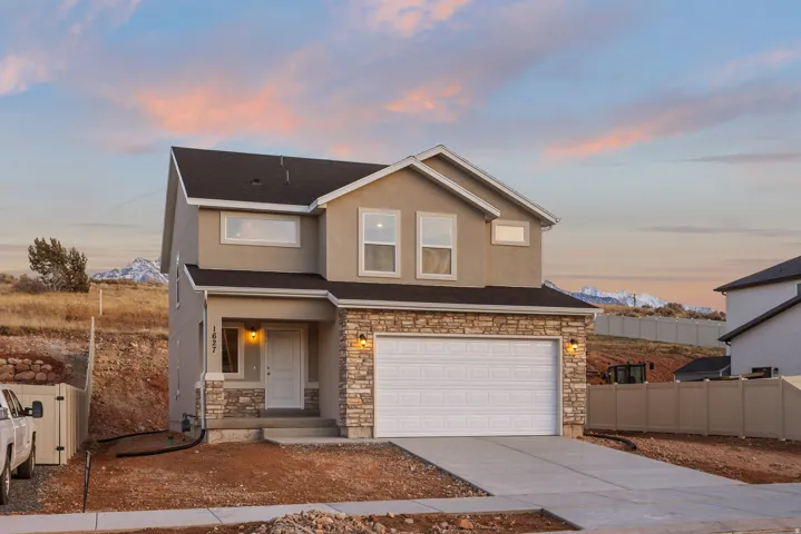 Two-story exterior with a covered entry, stone facade accents, an attached garage, and a concrete driveway