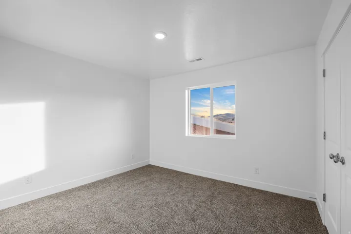 Neutral tone wall finishes, recessed ceiling lighting, a window with exterior scenery, plush carpeting, and white trim