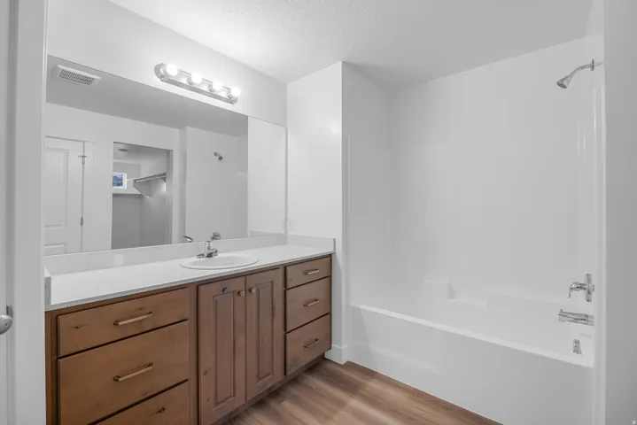 Vanity with wood-finish cabinetry, white countertop, and integrated sink