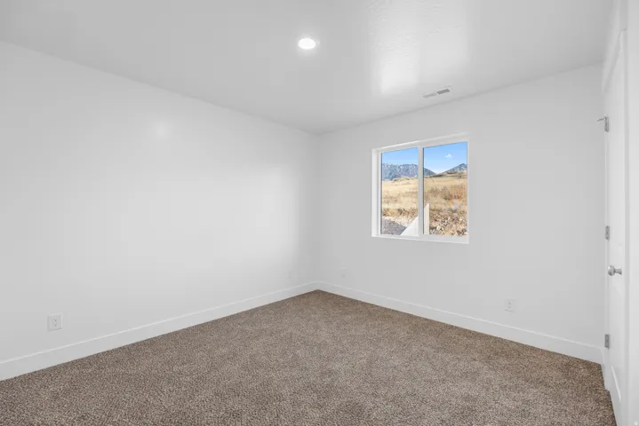 Recessed ceiling lighting, neutral carpeting, white wall finishes, and a single window with mountain scenery