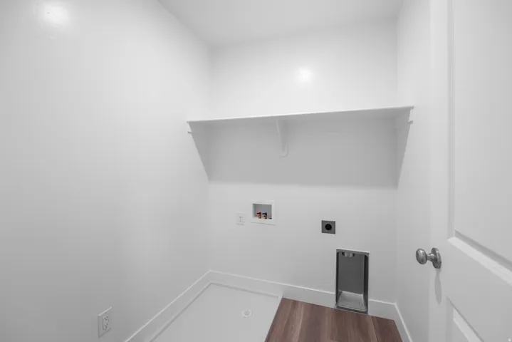 Dedicated laundry space with a built-in white shelf, wood-finish flooring, and a utility sink basin