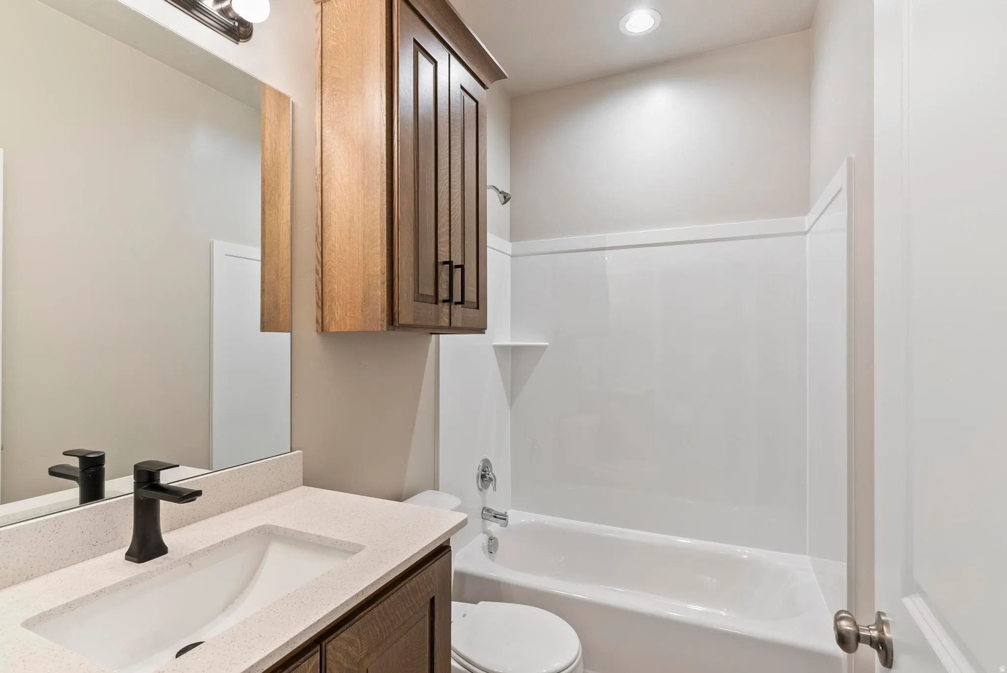 Bathroom featuring a vanity with an integrated sink, light-toned countertop, dark wood-finish cabinetry, and a full-size mirror