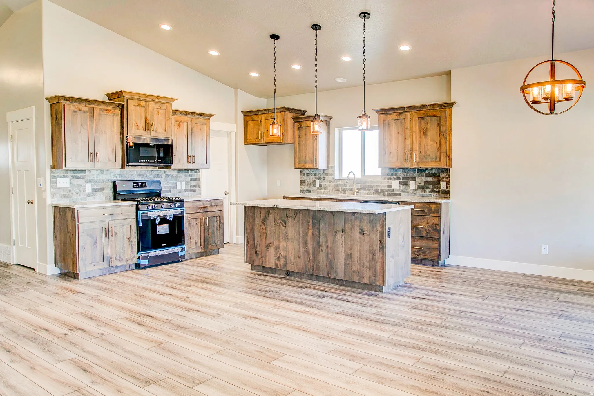 Vaulted ceiling with recessed lighting, wood-finish flooring, wood cabinetry, stone countertops, and a full tile backsplash