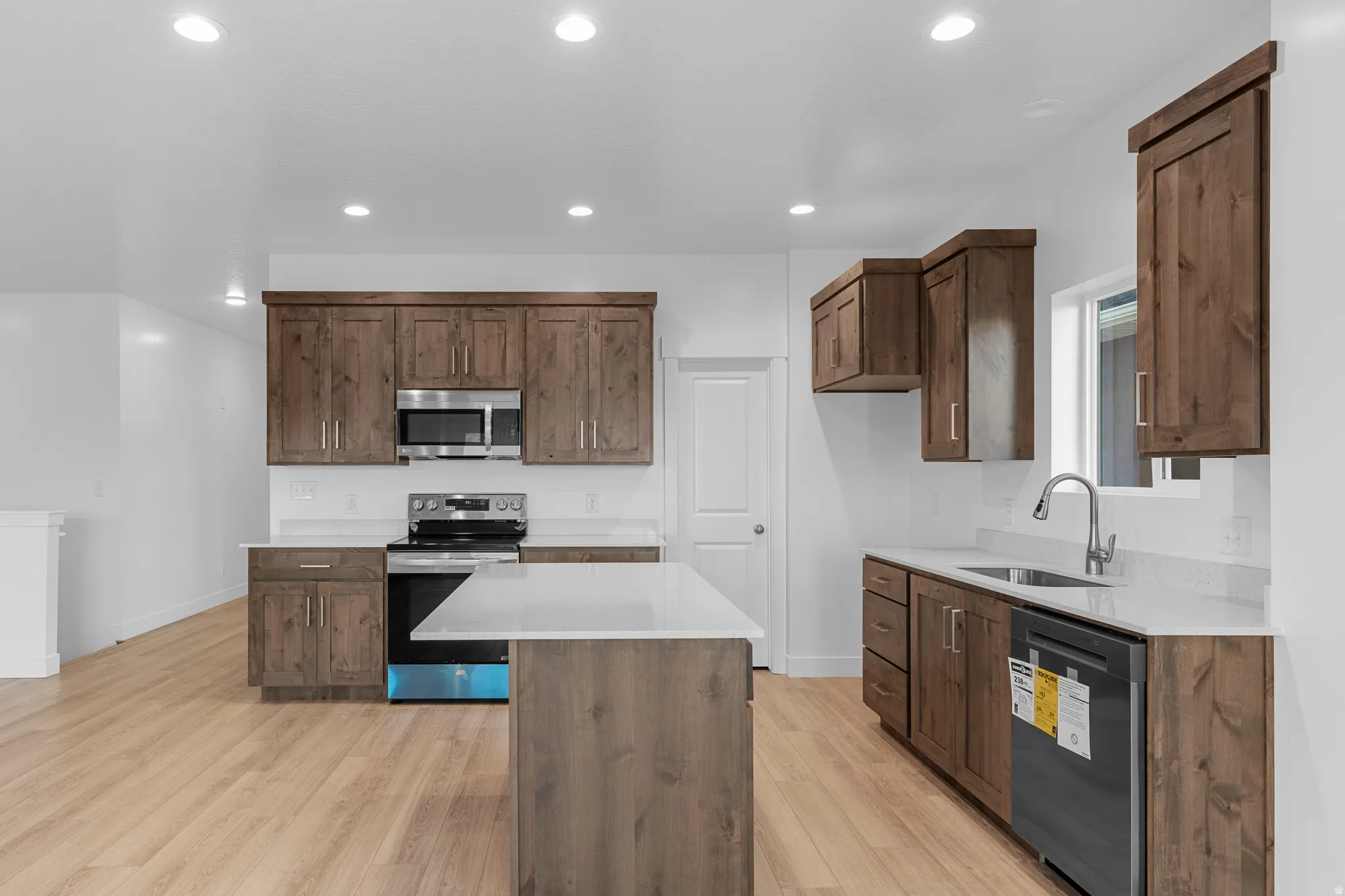 Wood-finish flooring throughout, recessed lighting, wood cabinetry, stainless steel appliances, and white countertops