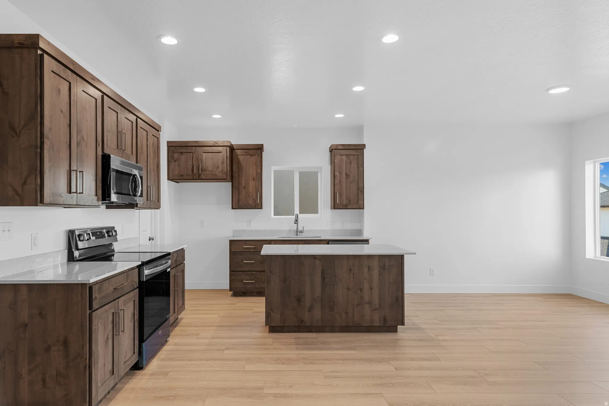 Open-concept kitchen with wood-finish flooring, recessed lighting, and a kitchen island
