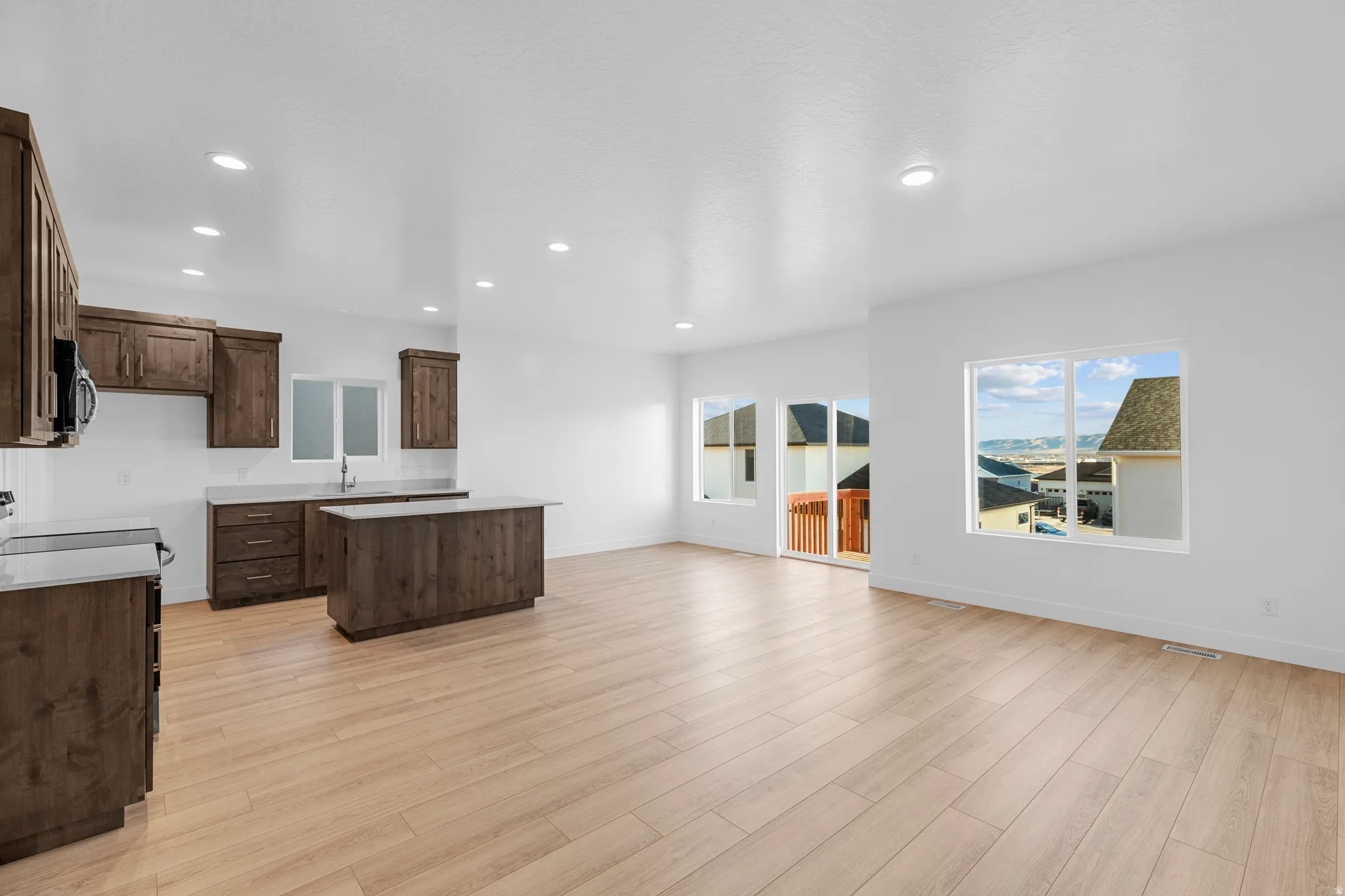 Open-concept living area with wood-finish flooring, recessed lighting, and white walls