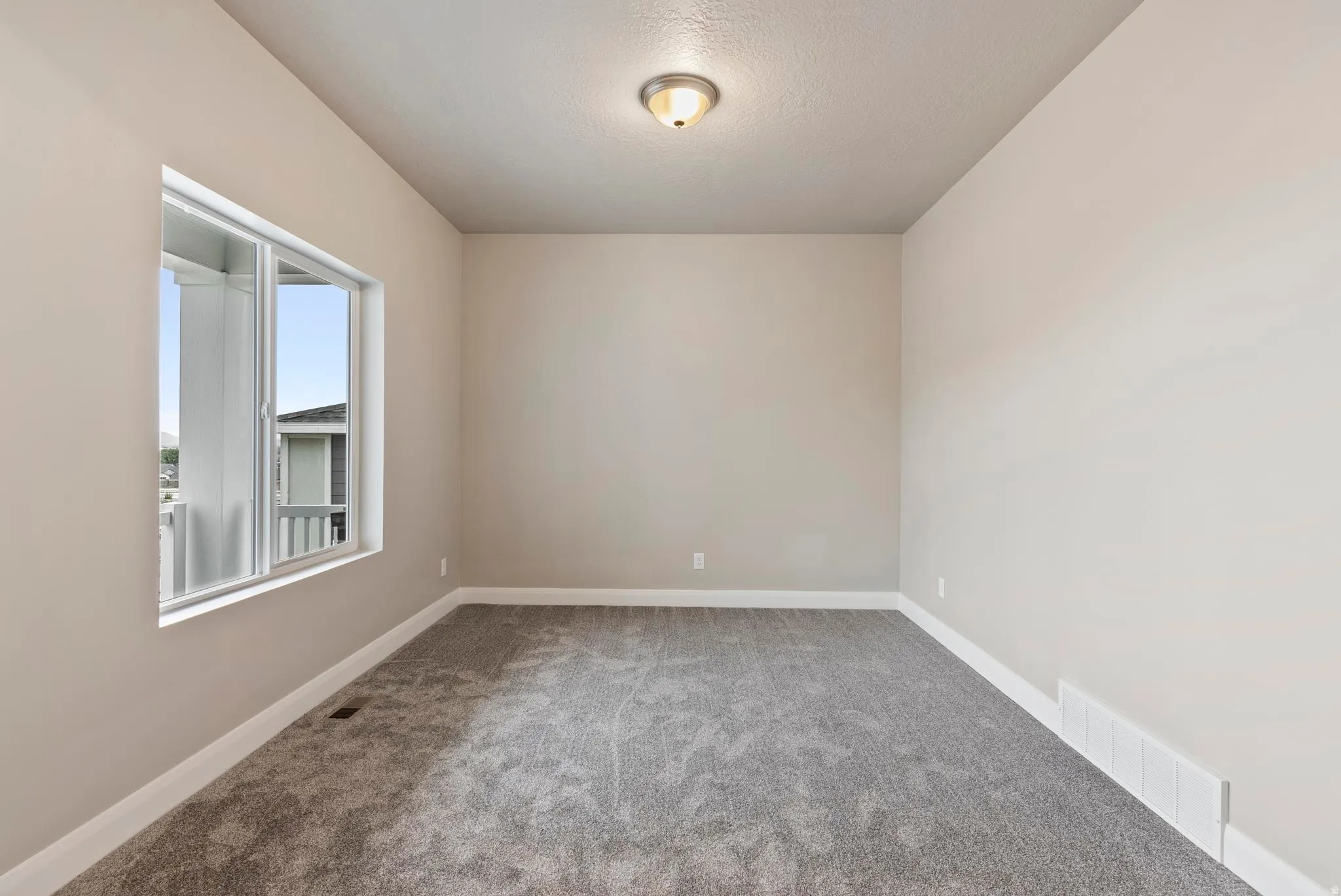 Neutral wall paint, plush carpet flooring, white trim, recessed lighting, and a single window
