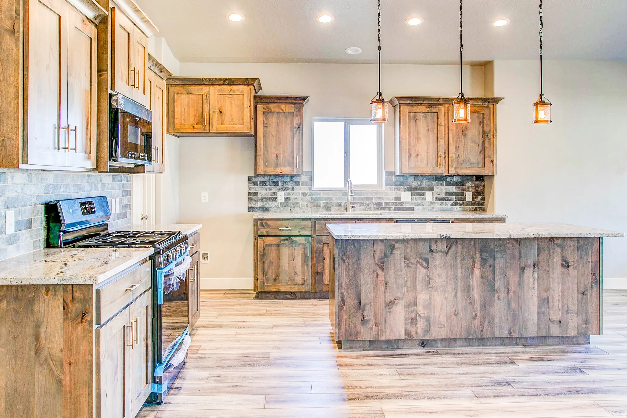 Kitchen featuring a large island, wood-finish cabinetry, stainless steel appliances, and pendant lighting