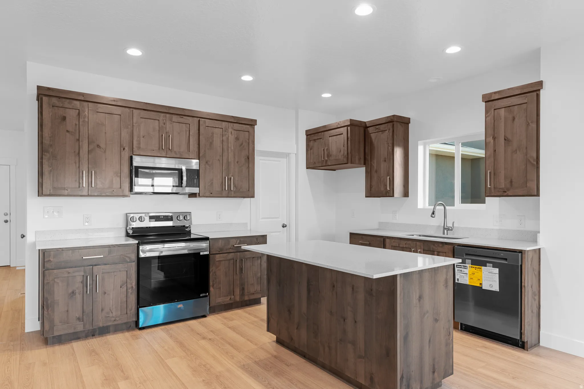 Kitchen with wood-finish cabinetry, light-toned countertops, and wood-finish flooring
