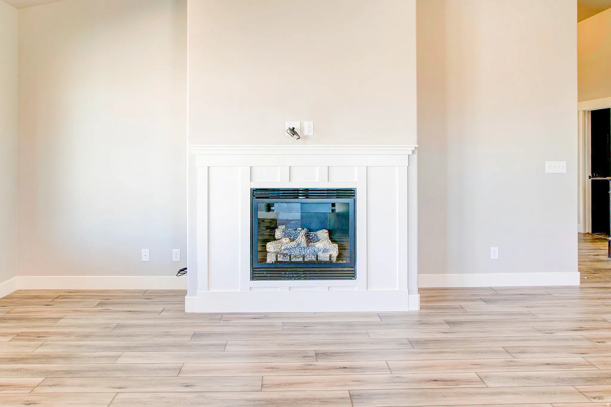 Contemporary fireplace with a white mantel and surround, featuring wood-finish flooring