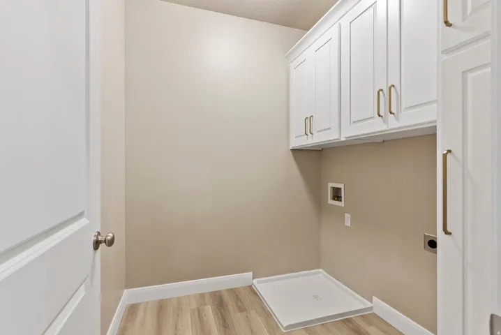 White shaker-style cabinetry with gold-tone hardware, wood-finish flooring, and light neutral wall paint