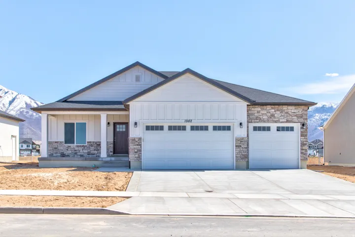 Contemporary single-story residence with stone and siding exterior, covered porch entry, and a three-car garage