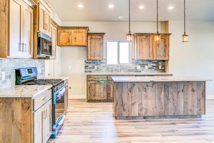 Kitchen featuring a large island, wood-finish cabinetry, stainless steel appliances, and pendant lighting