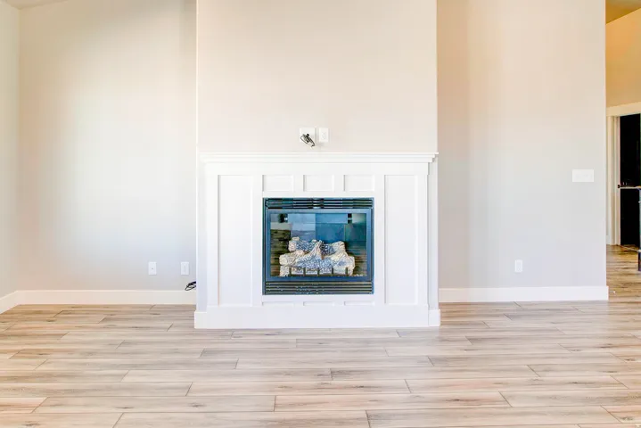 Contemporary fireplace with a white mantel and surround, featuring wood-finish flooring